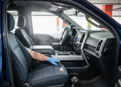 Technician shampooing and steam cleaning carpets and seats.