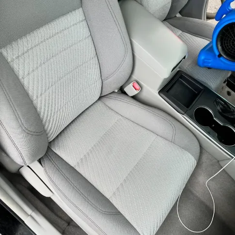 On-site technician working on car seat after cleaning, showing tools and drying setup