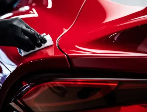 Close-up of a car receiving ceramic coating application in a sheltered space.