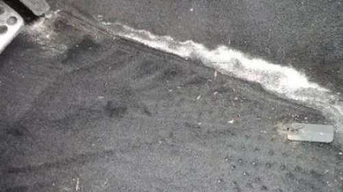 Gloved hands wiping salt stains from car carpet.