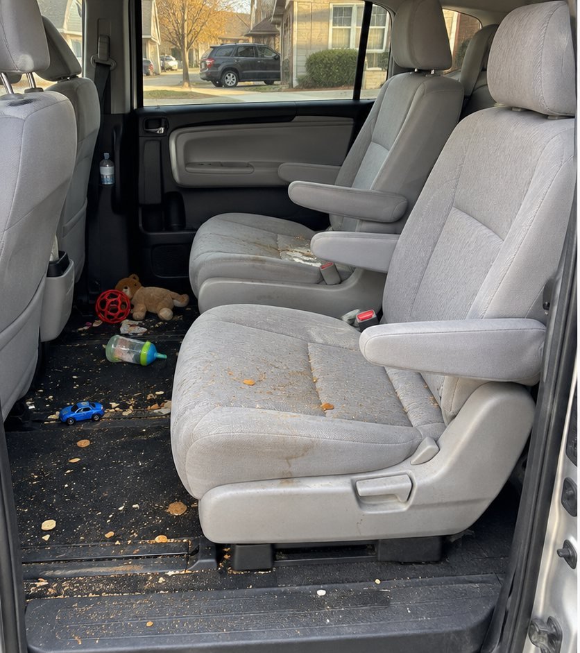 Minivan second-row captain's chairs with crumbs, spilled snacks and children's toys scattered on the floor