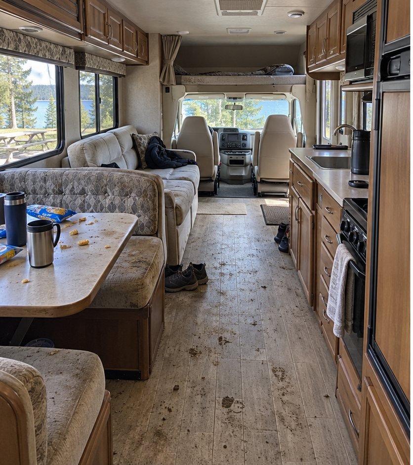 RV kitchen and dinette walkway with a muddy, tracked-in floor and cluttered table