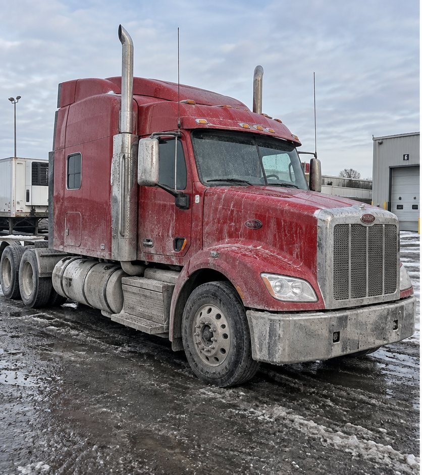 Red semi-truck tractor front end coated in road film and dust